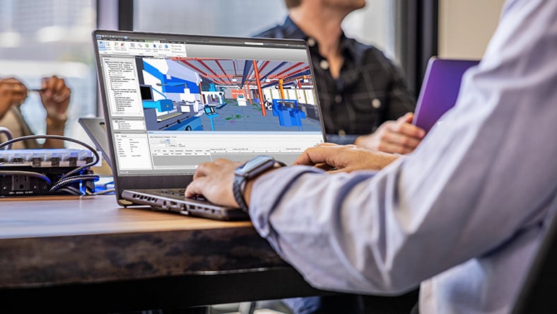 An architect works on a building model on a laptop.
