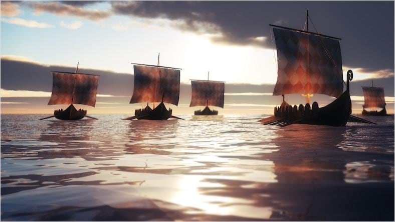 A video game still shows Viking ships sail on sunlight-dappled water.