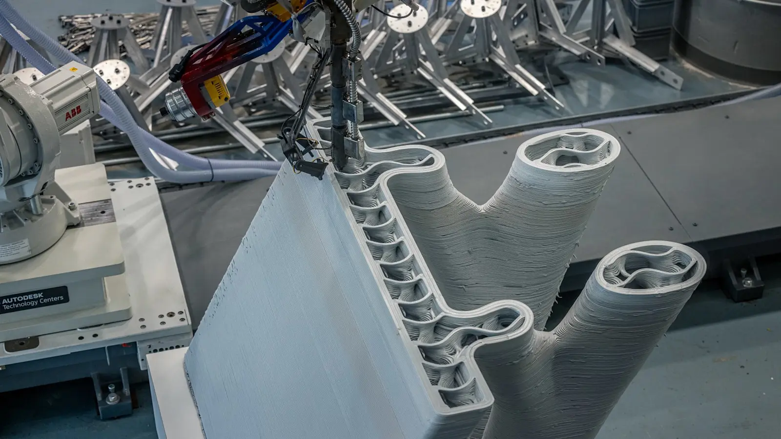 Un braccio robotico estrude il materiale plastico per un test del ponte stampato in 3D.