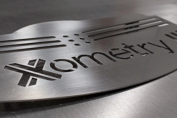 Xometry logo on a piece of metal