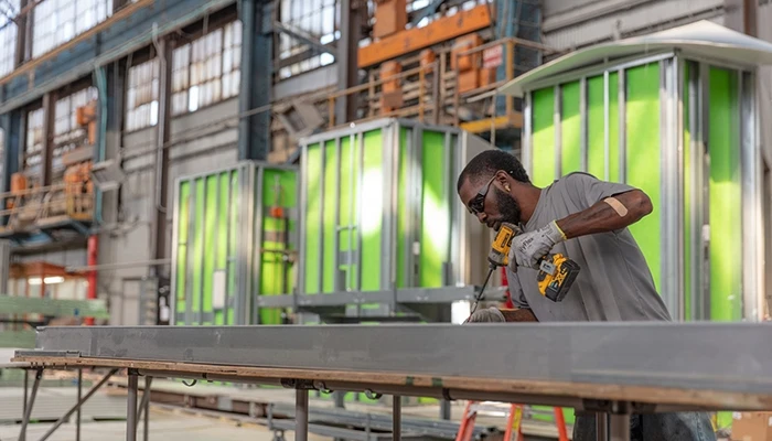 A man uses a drill on a steel beam