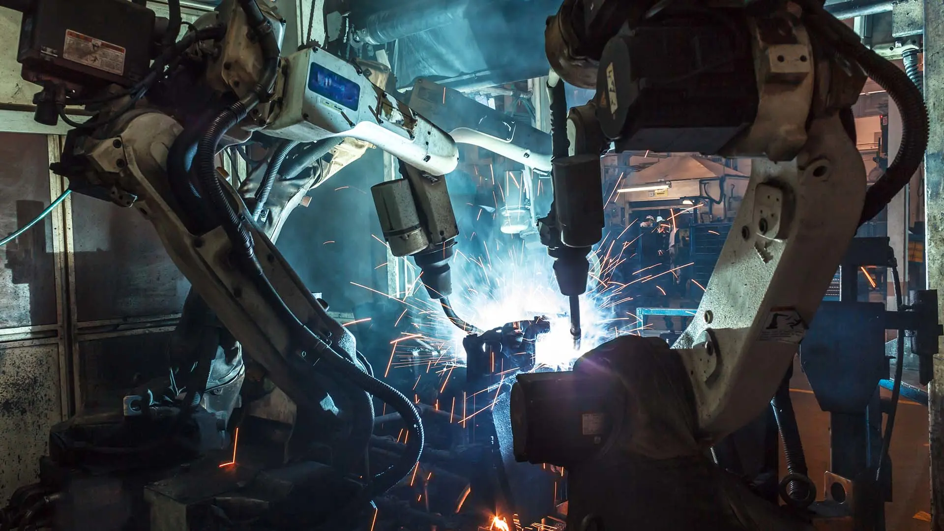 An einer Fertigungsstraße schweißen Roboterarme Autoteile zusammen.