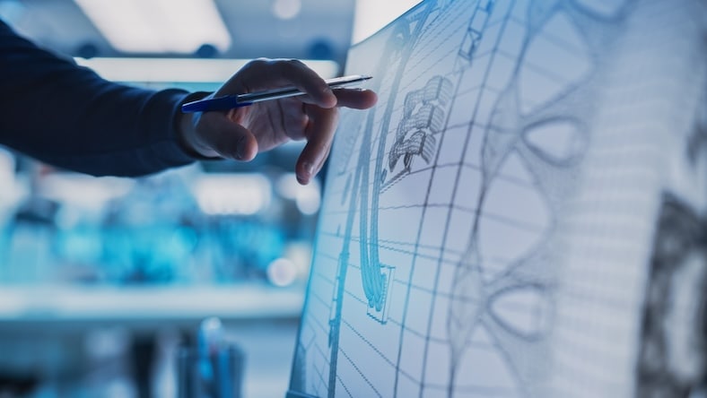 A close-up of a desktop computer monitor screen shows a model of a jet engine part.