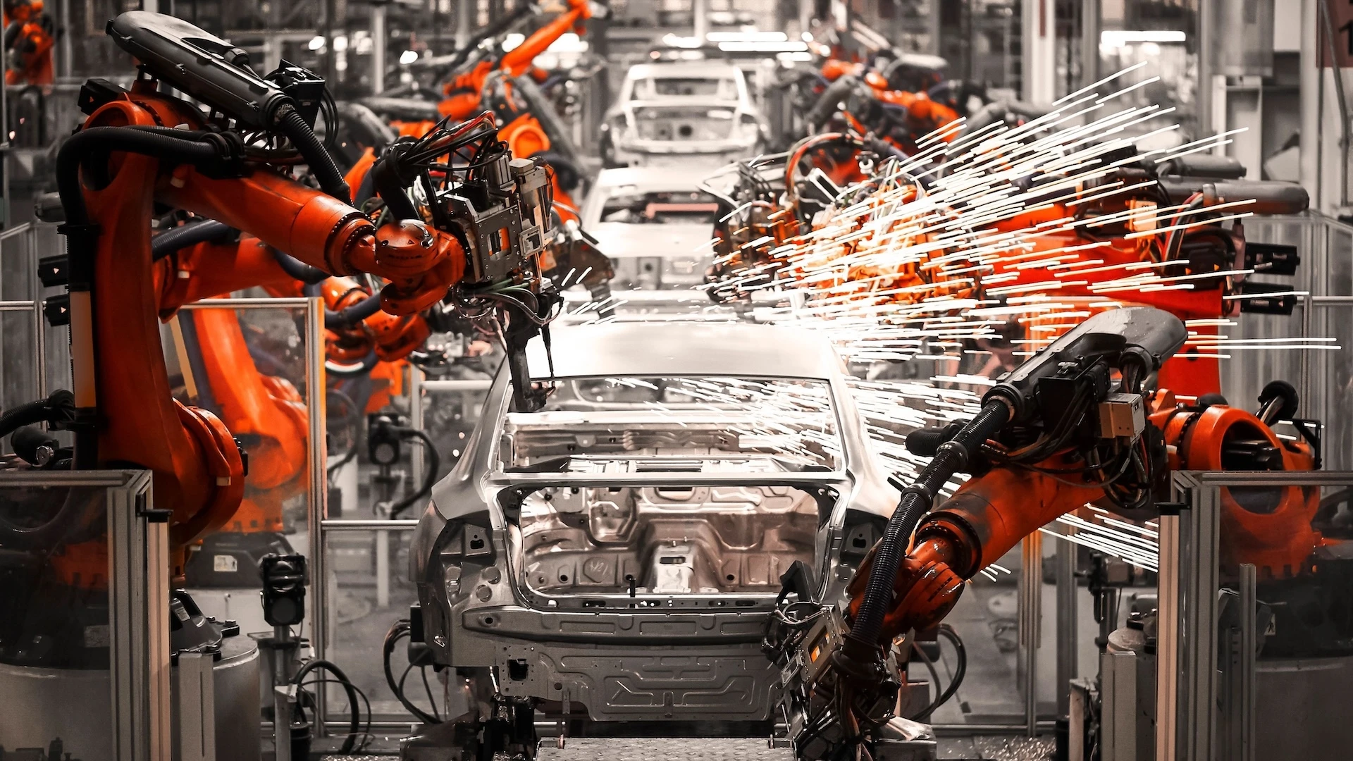 robot arms working on cars in a factory assembly line
