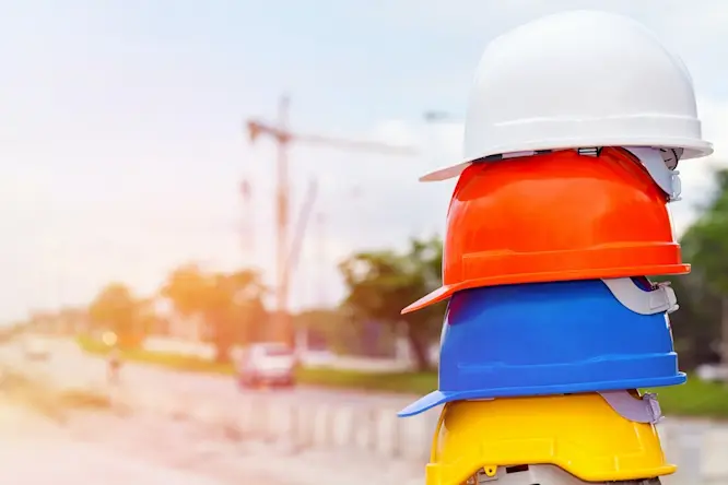 A stack of multicolored hard hats on a construction site