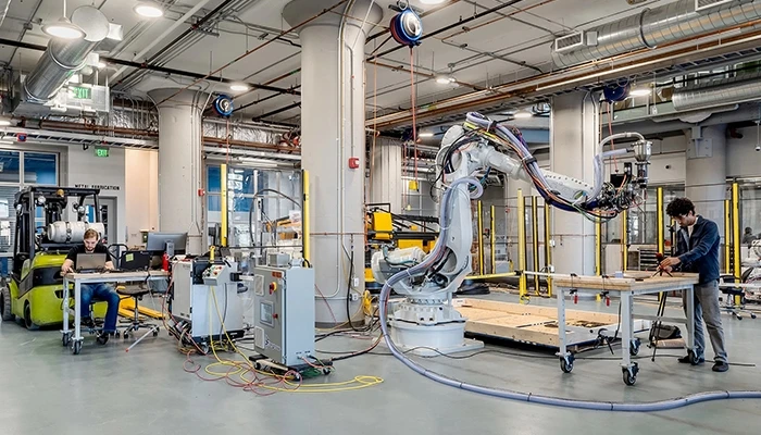 Manufacturing scene with two men and a large white industrial robot