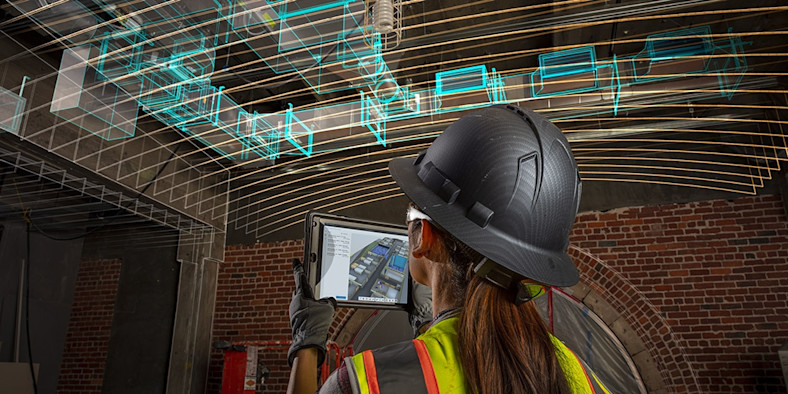 Construction worker looking at a tablet inside of a building, with digitally imposed lines on the image representing data.