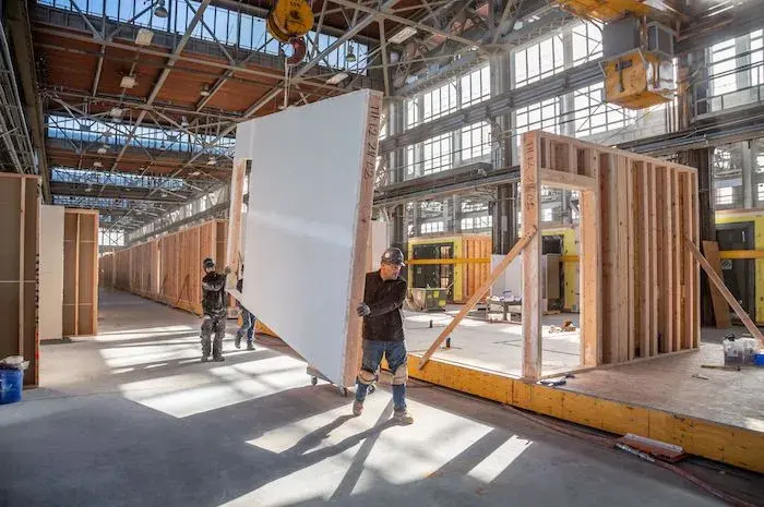 Workers at Factory_OS in Vallejo, CA, carry panels designed for modular homes. 