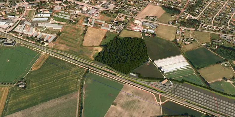 An aerial view of railroad tracks, grassland, and homes