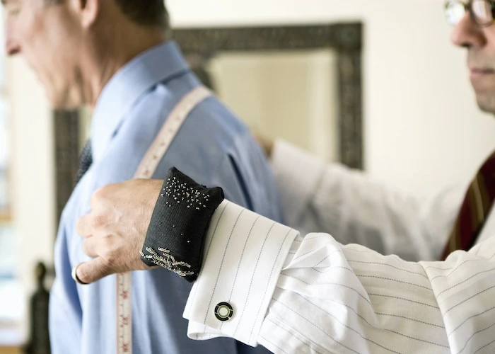 Tailor measuring a man's shoulders for a suit