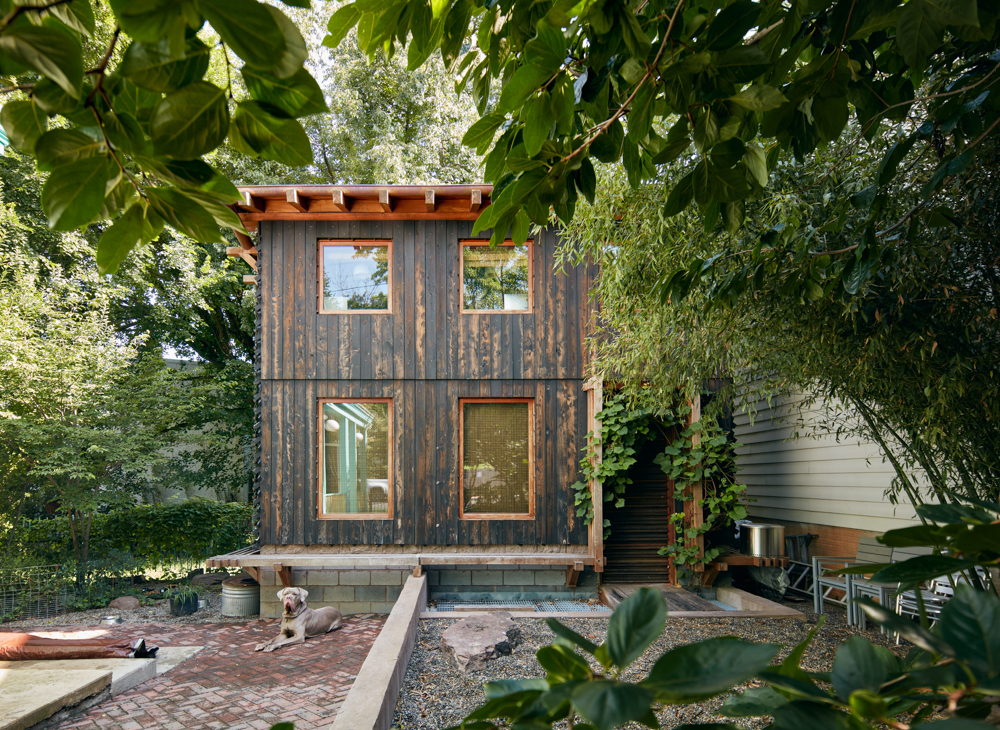 Exterior of Grass House with wood siding and brick walkway