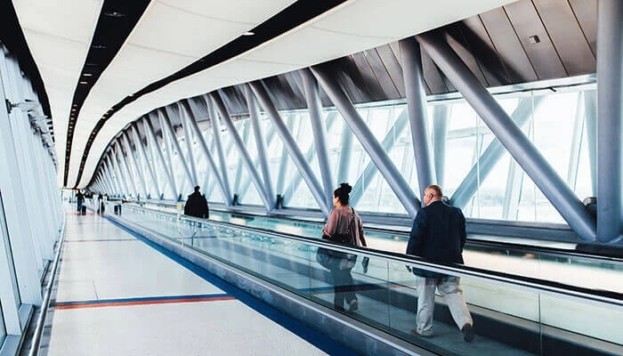 People walk on a moving sidewalk in an airport.