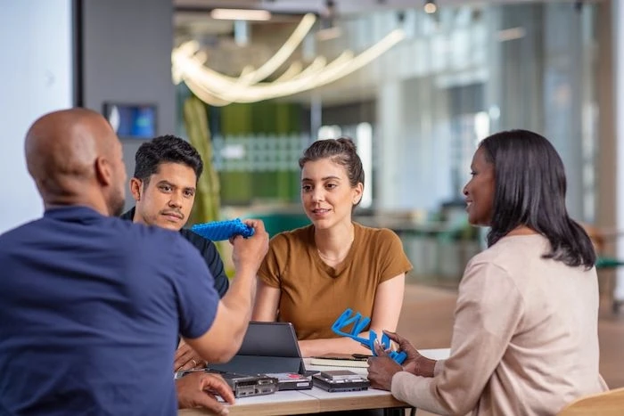 people sitting around a table examining a 3D printed object