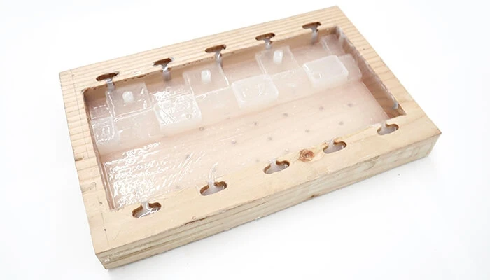 A wood-and-silicone mold used to form tiles from shredded plastic 