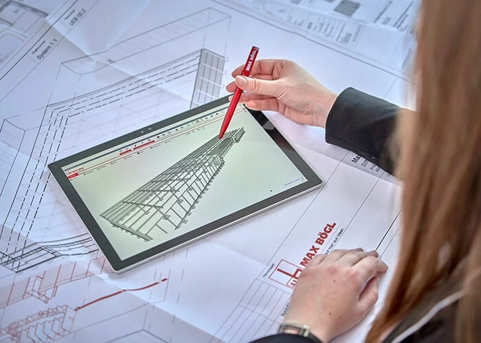 A woman works on a tablet showing a digital twin of a Max Bögl site.