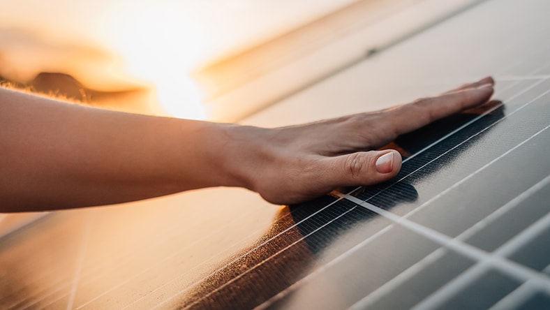 A person's hand slides across a solar panel.