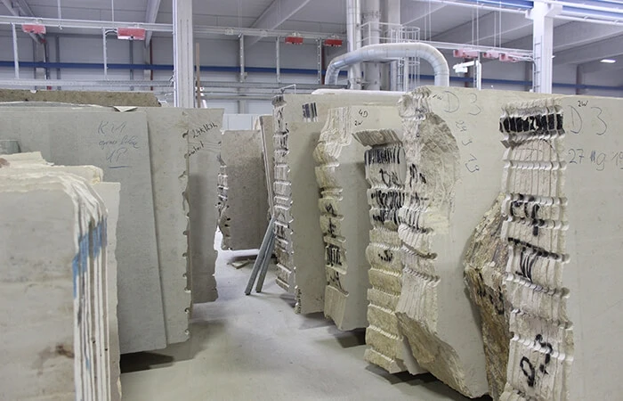 Large stone blocks sit in a factory, ready for cutting.