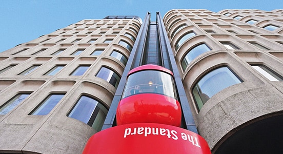 A red lift ascends the front of a modern destination hotel