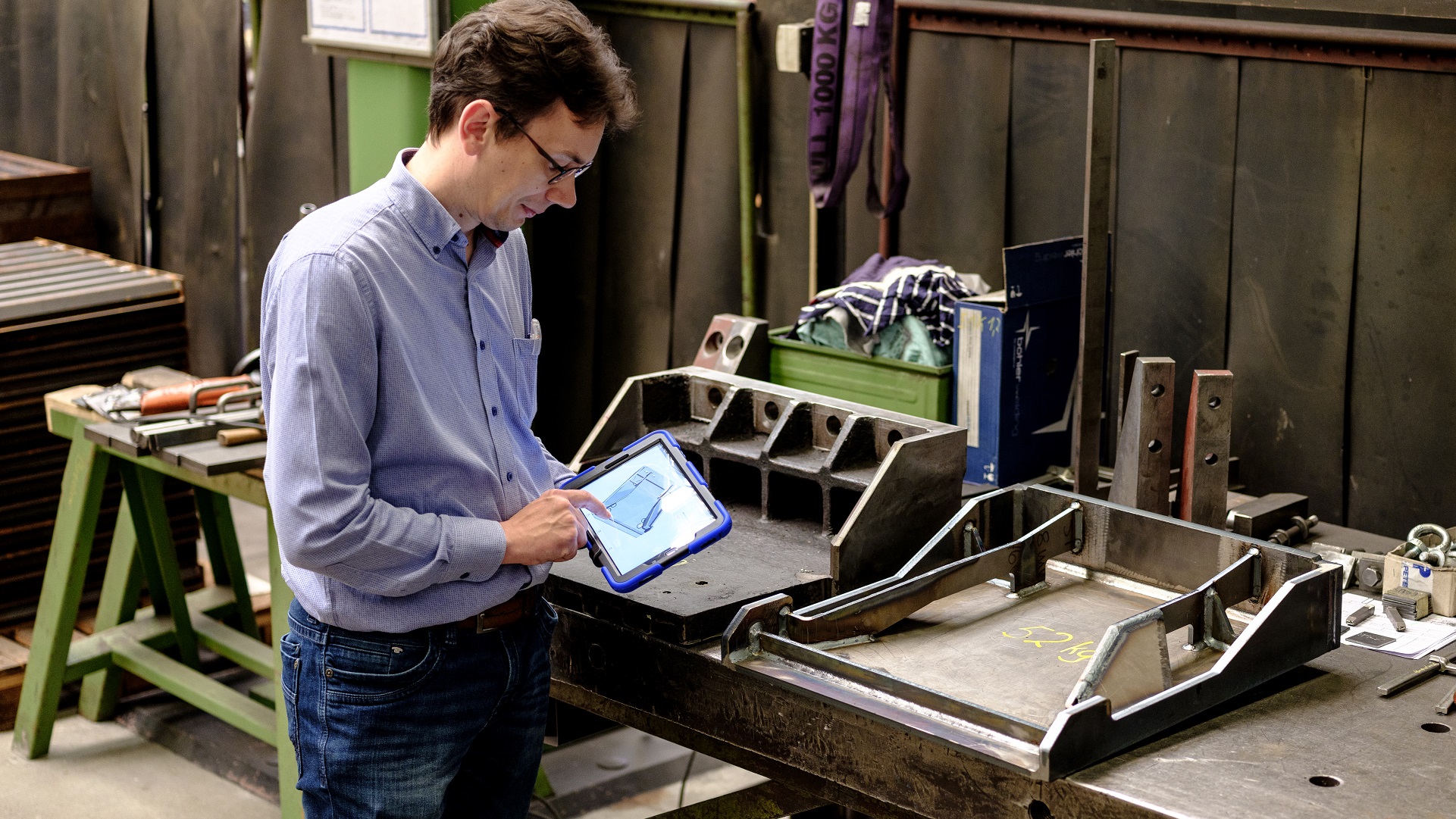 Engineer compares a generatively designed metal part to the design on a tablet screen. 