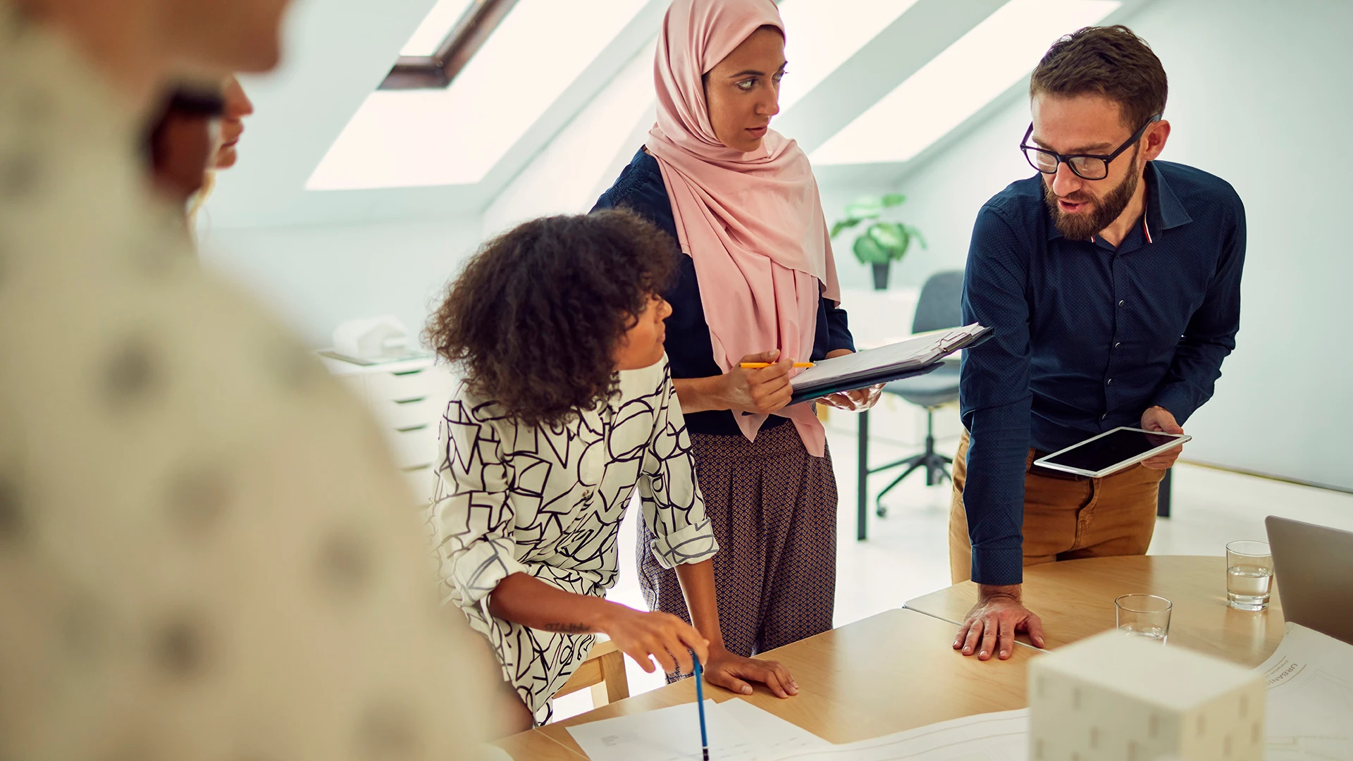  Un groupe disparate de professionnels travaille ensemble autour d’une table et passe en revue des plans et des documents.