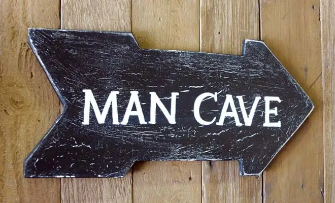 Close-up of right arrow sign with words "Man Cave" written on it