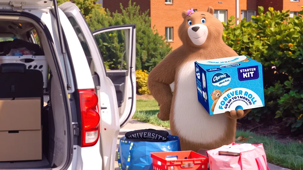 Molly the Charmin bear holding a box of Charmin Forever Roll while moving into her college dorm room