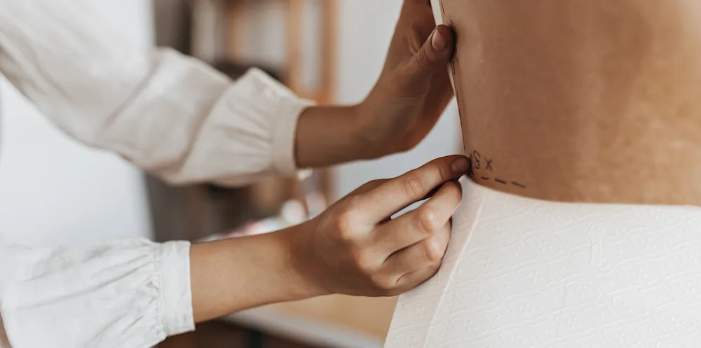 Primer plano de una costurera alterando un vestido de papel higiénico