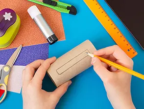 Person drawing on a Charmin toilet paper roll