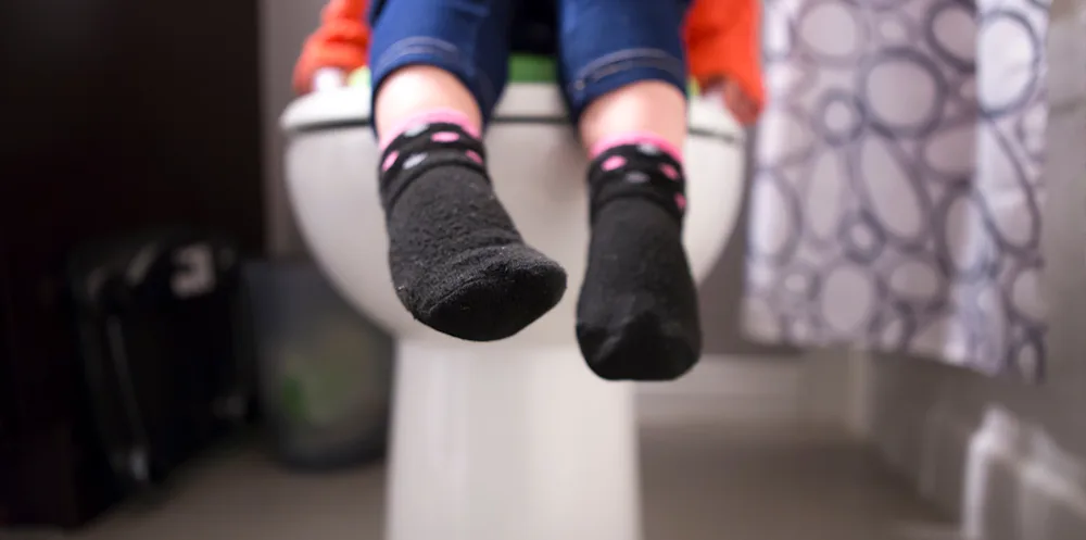 Niña pequeña sentada en el inodoro en un asiento de entrenamiento