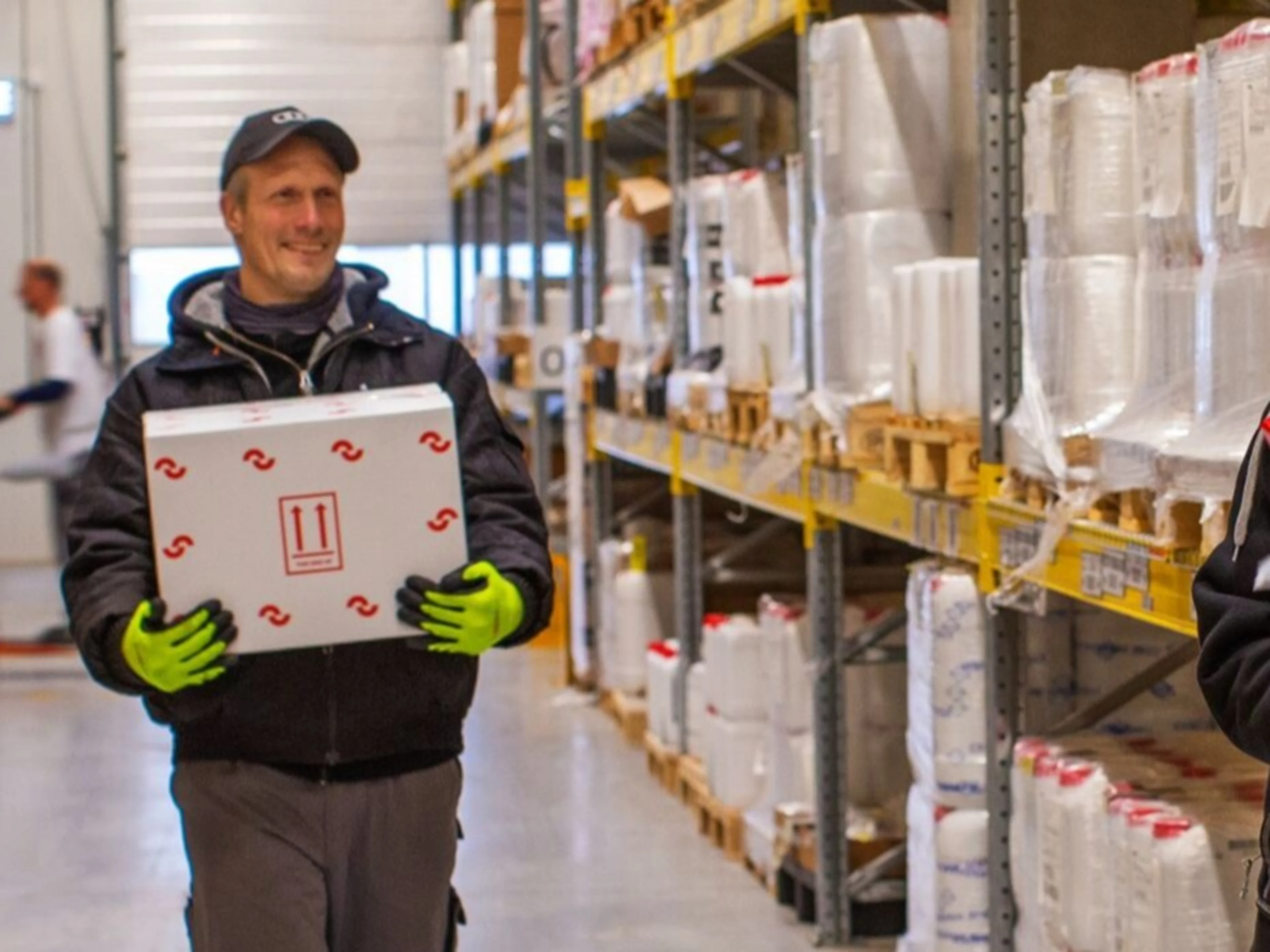 large-Oterra Hammerholmen colleagues chatting in warehouse man carrying box