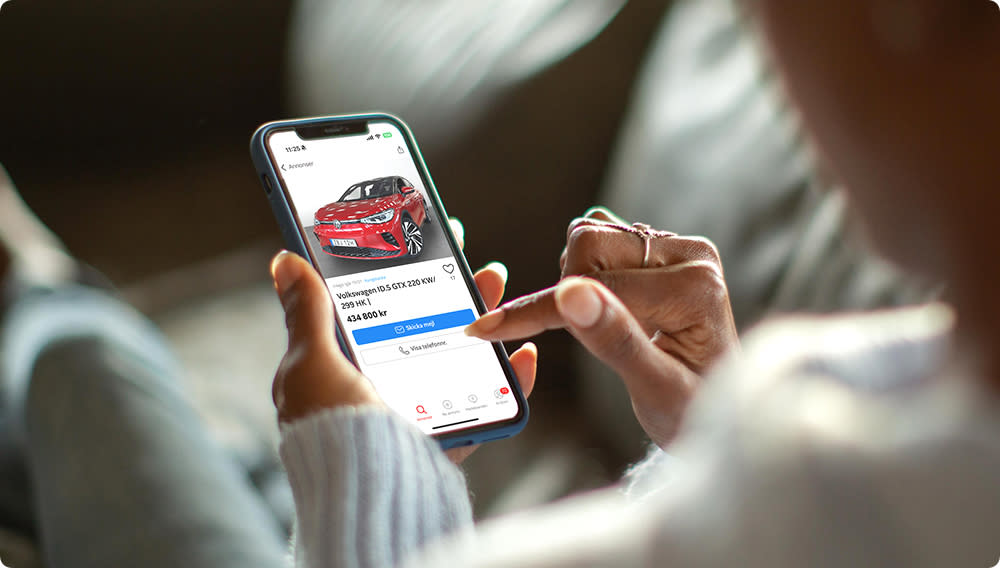 Mobiltelefon med bil på skärmen, i händerna på person