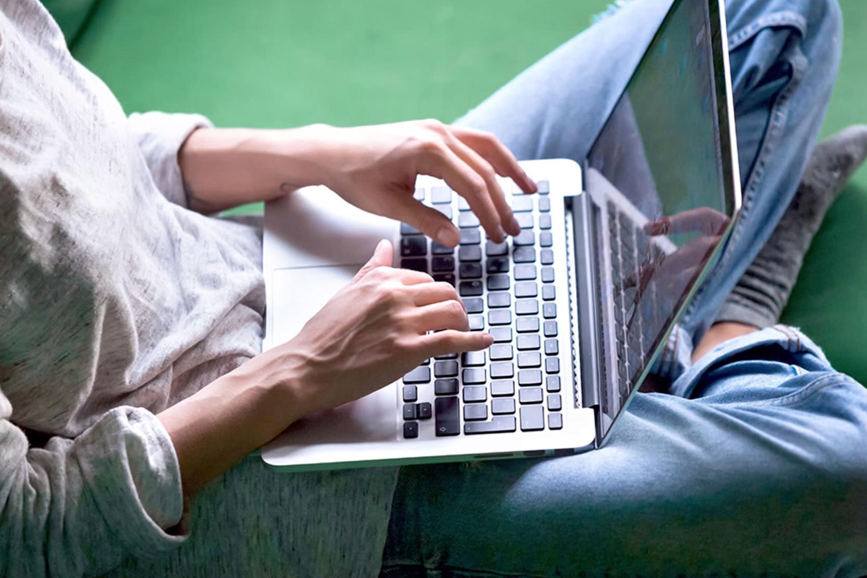 Närbild på laptop i knä, grön bakgrund