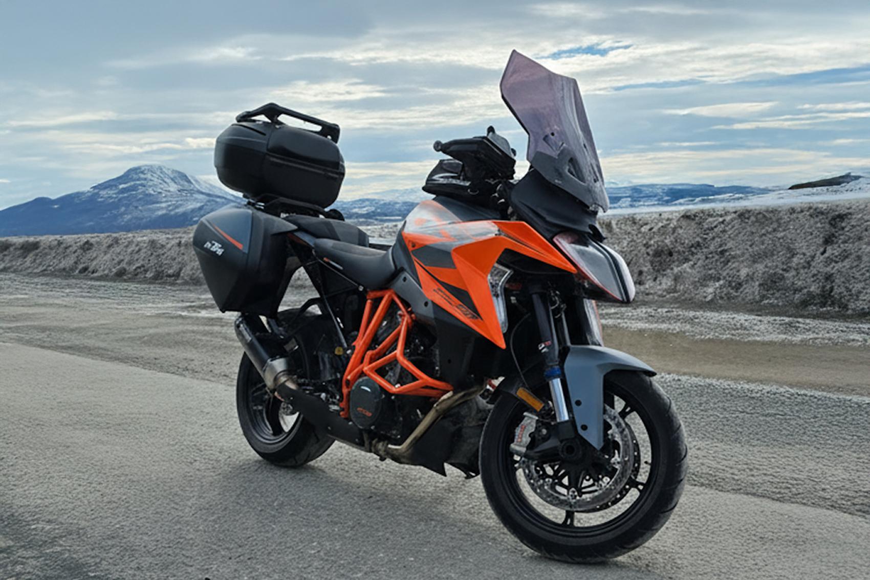 Motorcykel på karg väg med snövall i bakgrunden