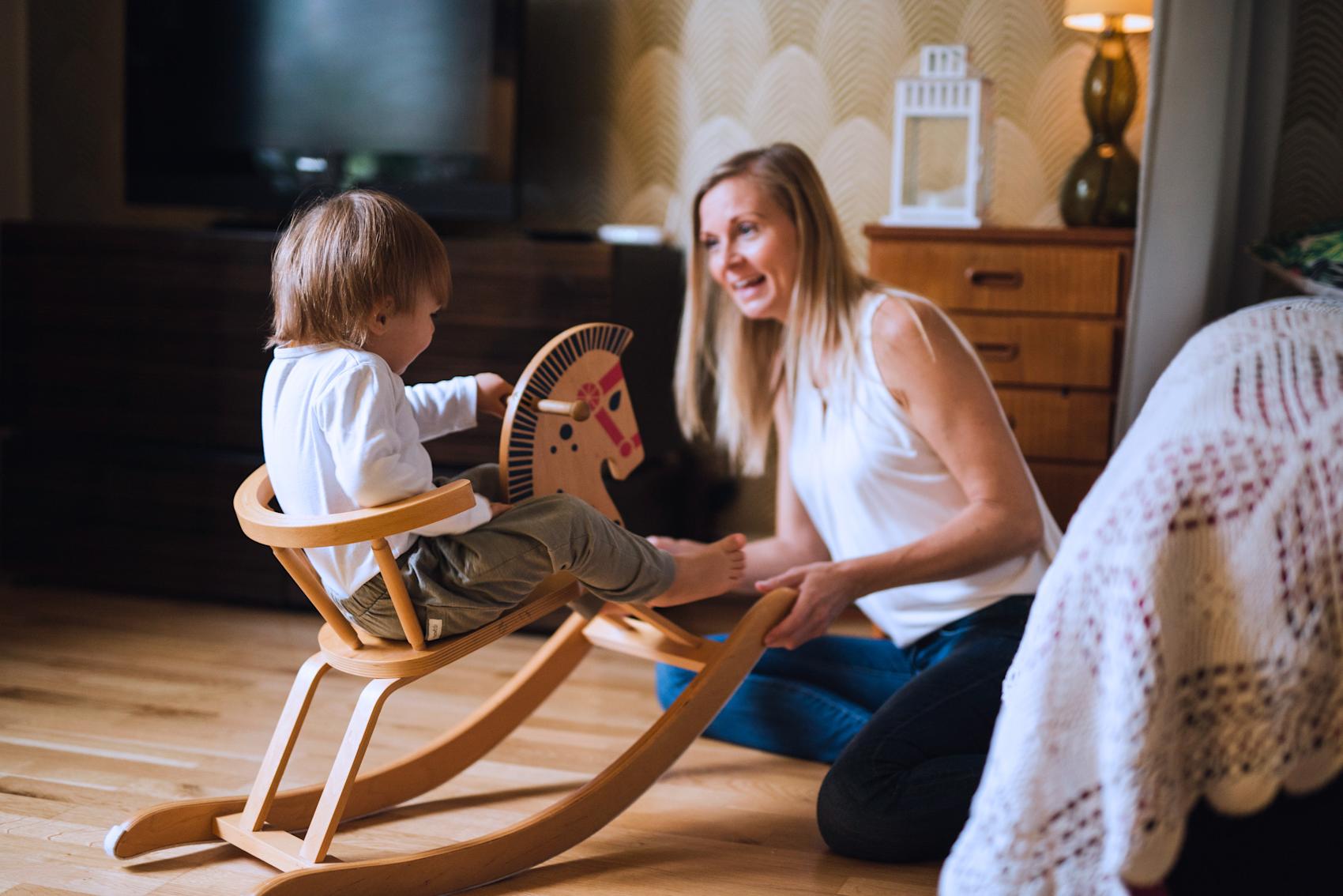 Ett barn rider på hästgunga bredvid sin mamma