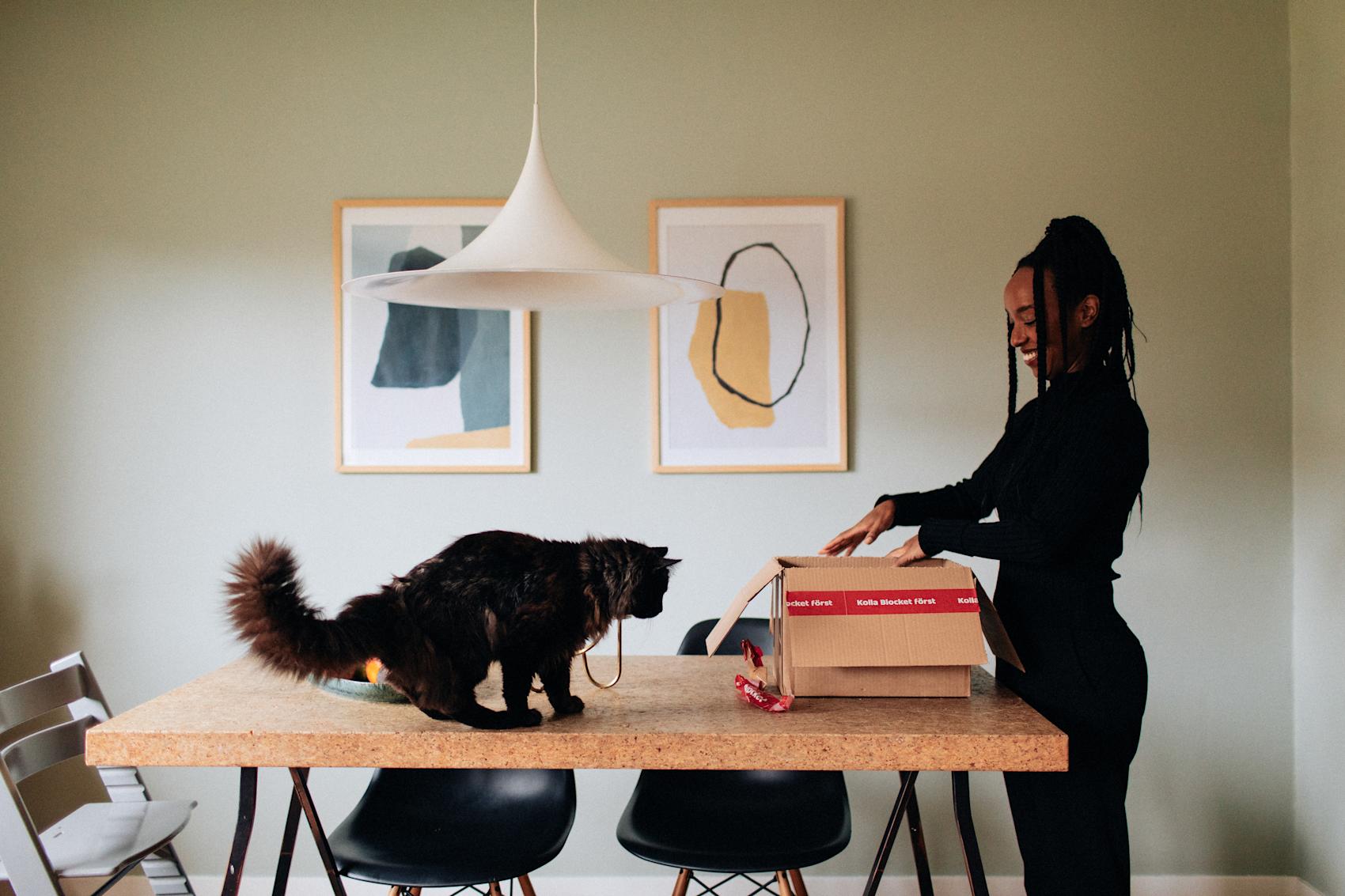 Kvinna med vid ett bord med en katt och en kartong