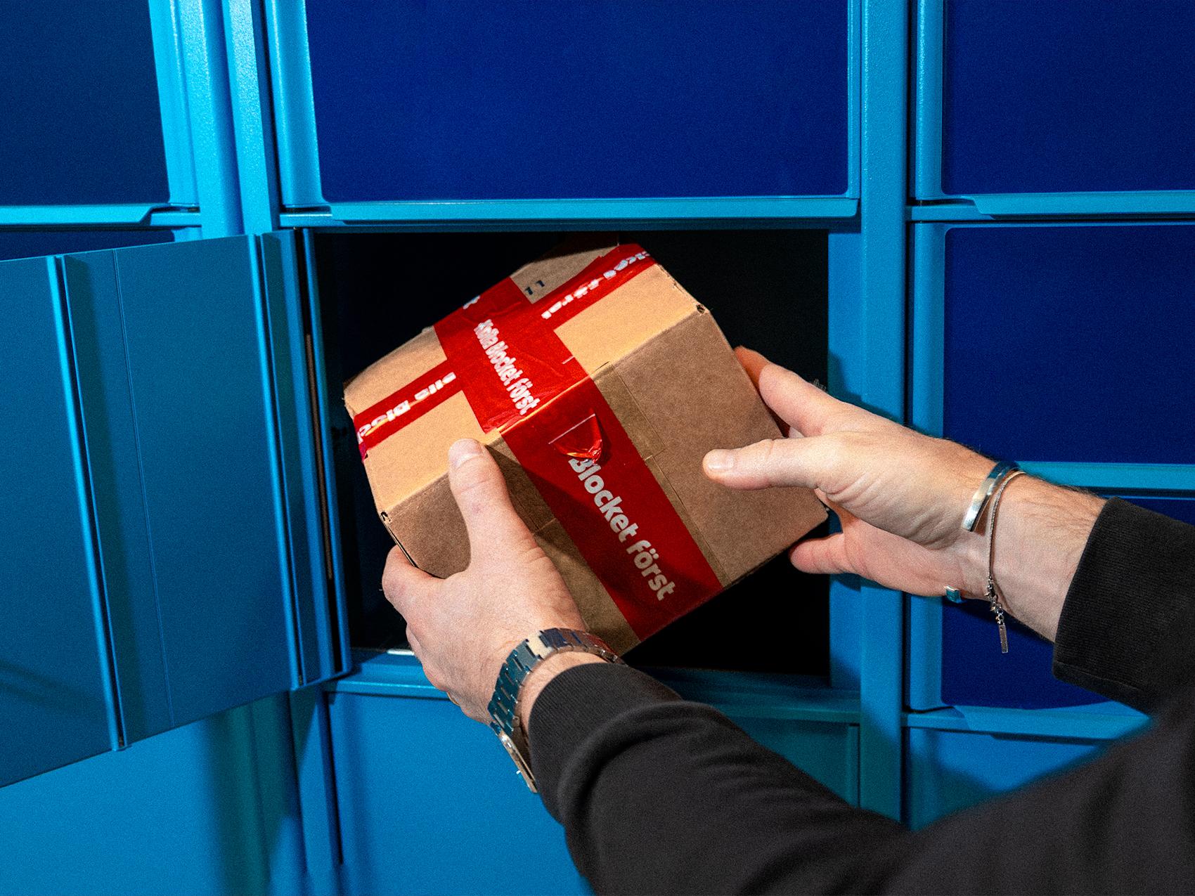 Paket med röd tejp hämtas från blå paketbox