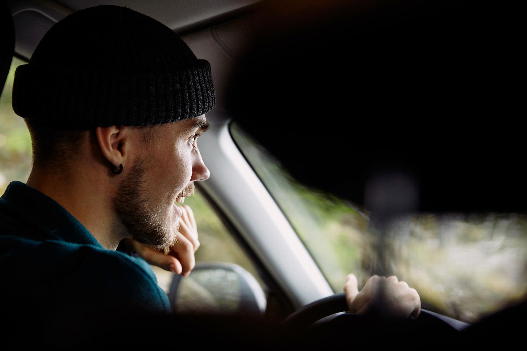 Man i svart mössa kör bil