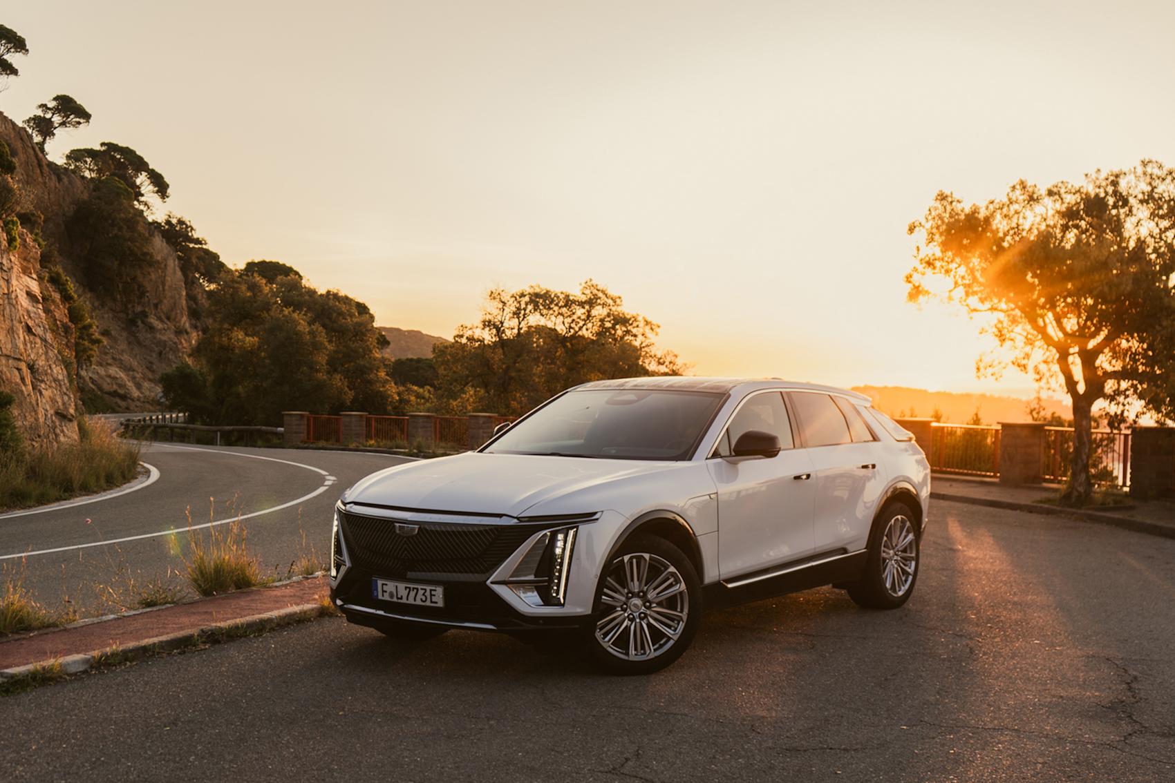 Vit bil parkerad på bergsväg vid solnedgång