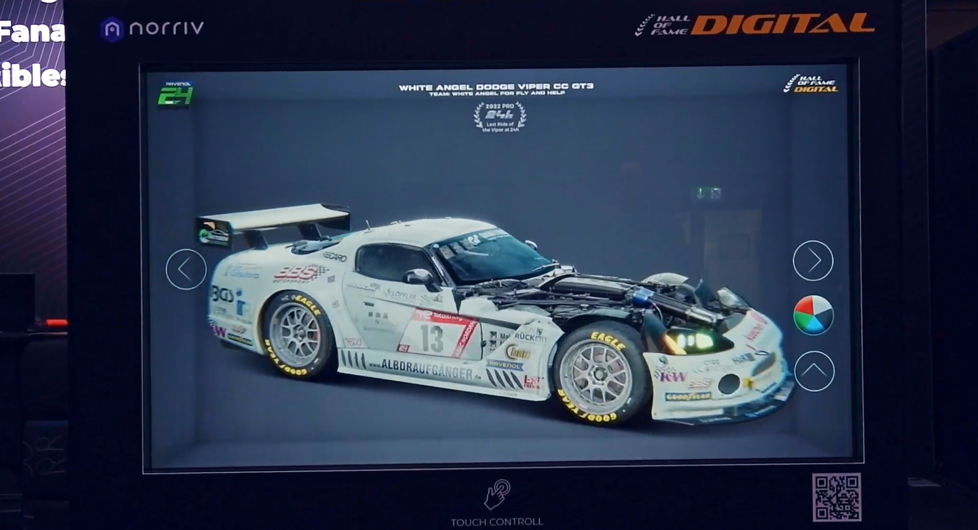 A digital display shows a detailed 3D model of a white Dodge Viper race car with racing decals, sponsor logos, and the hood open to reveal the engine. The screen has a circular menu on the right and control icons below.