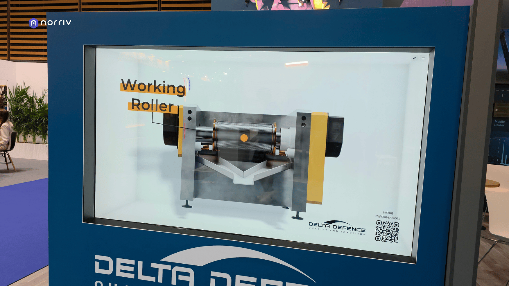 Close-up of a 3D machine model labeled Working Roller in DELTA-DEFENCE's Hologram Box, with company branding and a QR code.