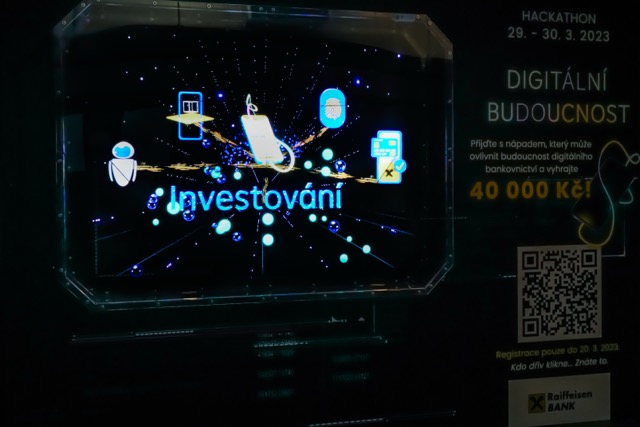 A digital screen displays the word Investování with financial and technology icons. On the right, event details for a digital banking hackathon, including dates, a QR code, and a 40,000 Kč prize, are shown.