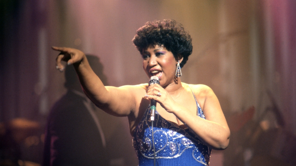 Aretha Franklin points in the distance while performing