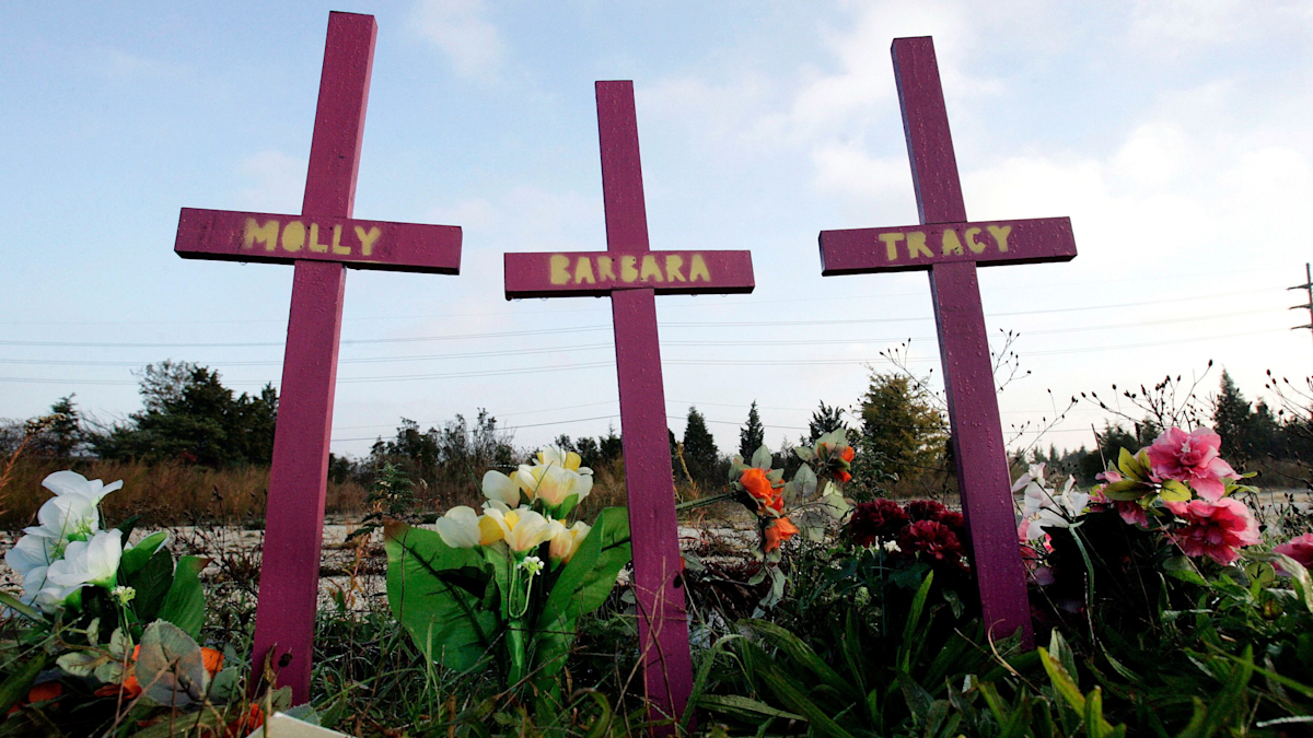 Three crosses stand surrounded by flowers. Each has a name painted on it: Molly, Barbara, Tracy.