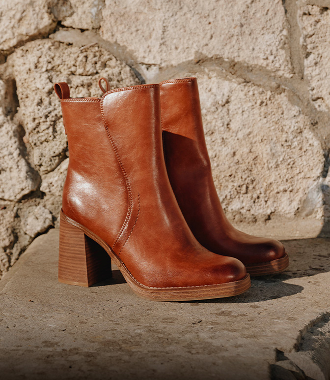 Braune Schnürstiefel mit Blockabsatz und Schnalle auf Steintreppe vor rustikaler Mauer im Herbstlicht