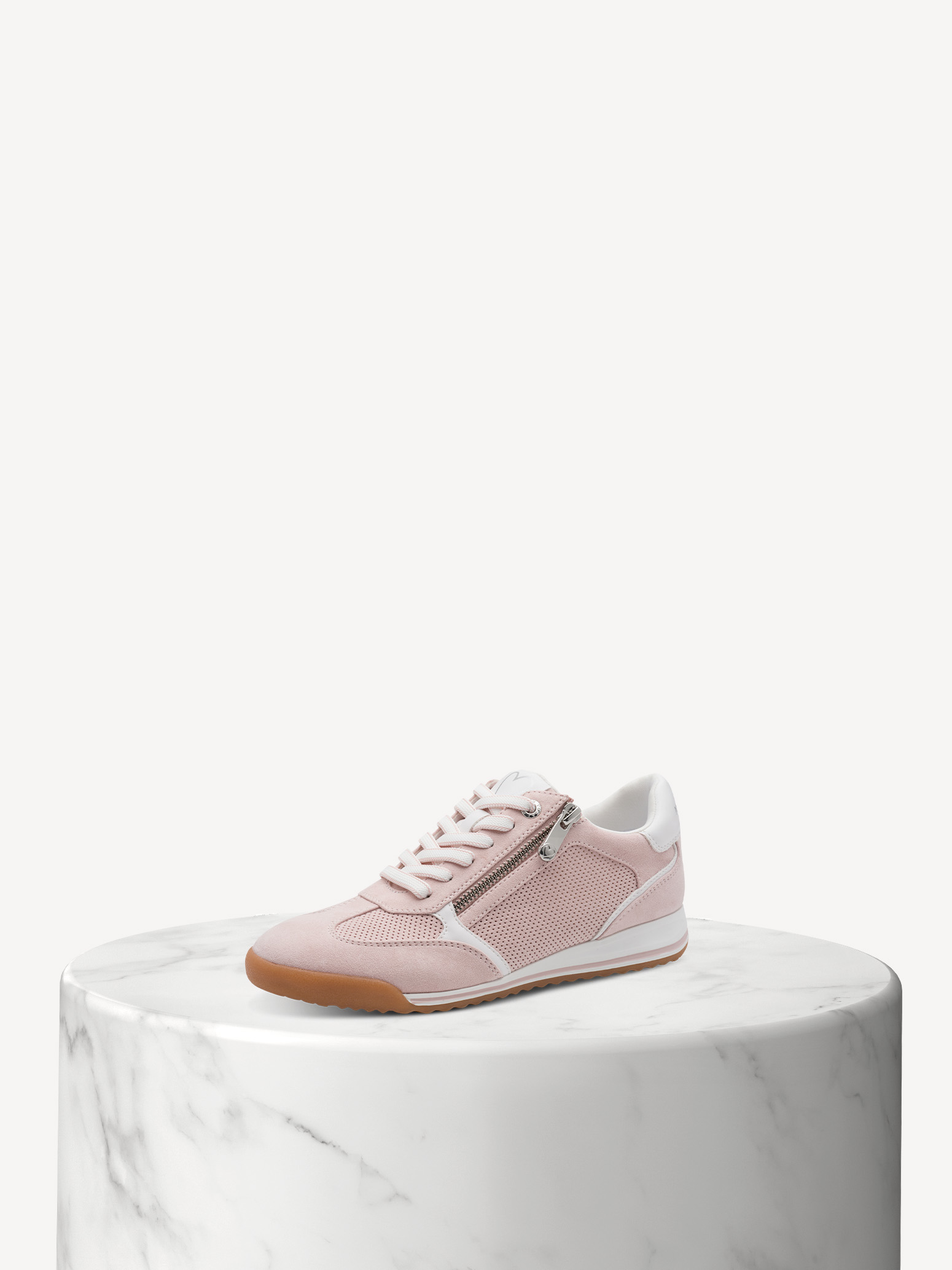 Sneaker rosa e bianca con cerniera su una base di marmo bianco su uno sfondo chiaro