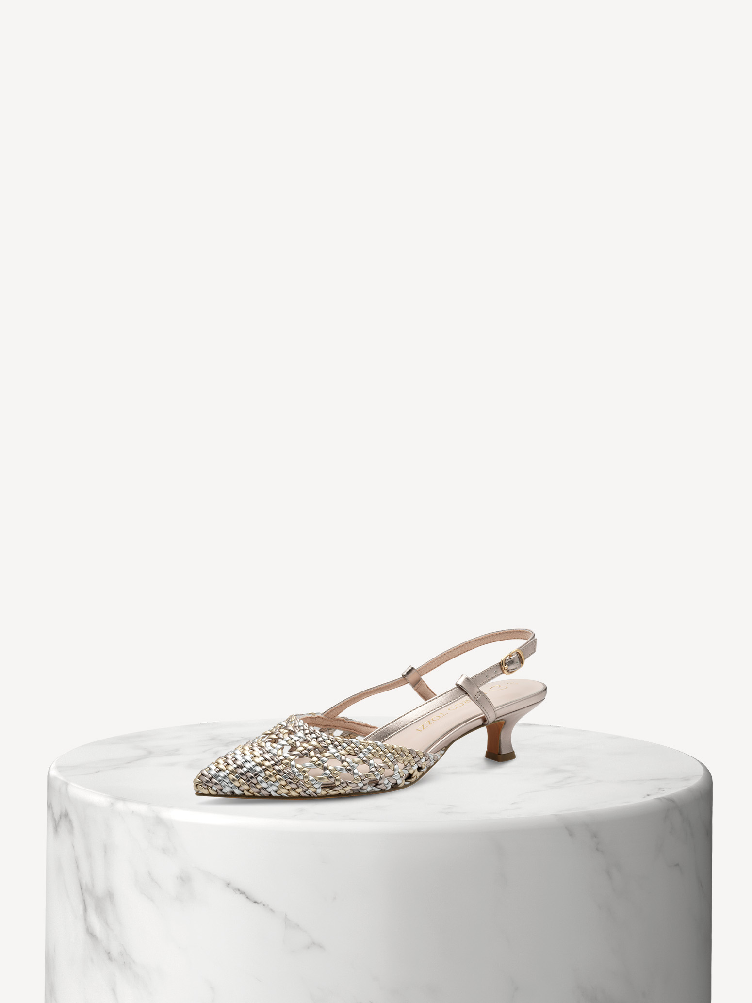 Elegante décolleté con tomaia intrecciata in tonalità metalliche e tacco a gattino su una base di marmo bianco