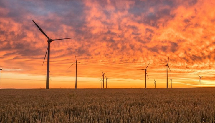 Windmills on an open field during sunset