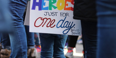 You girl wearing placard. "We can be heroes just for one day. David Bowie"