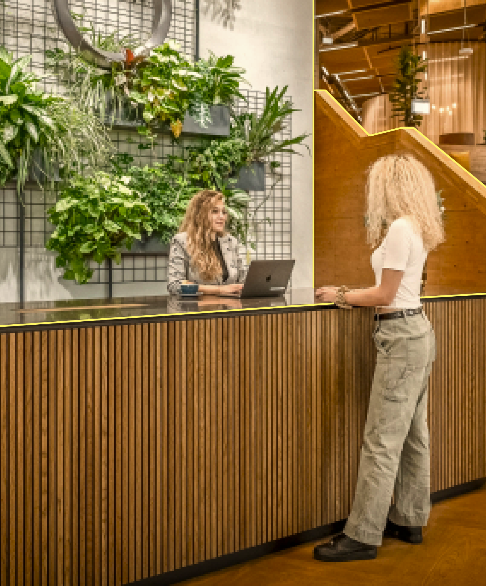 Zwei Frauen stehen am Empfang von einem schönen, moderner Bürogebäude mit viel Raum und vielen Pflanzen