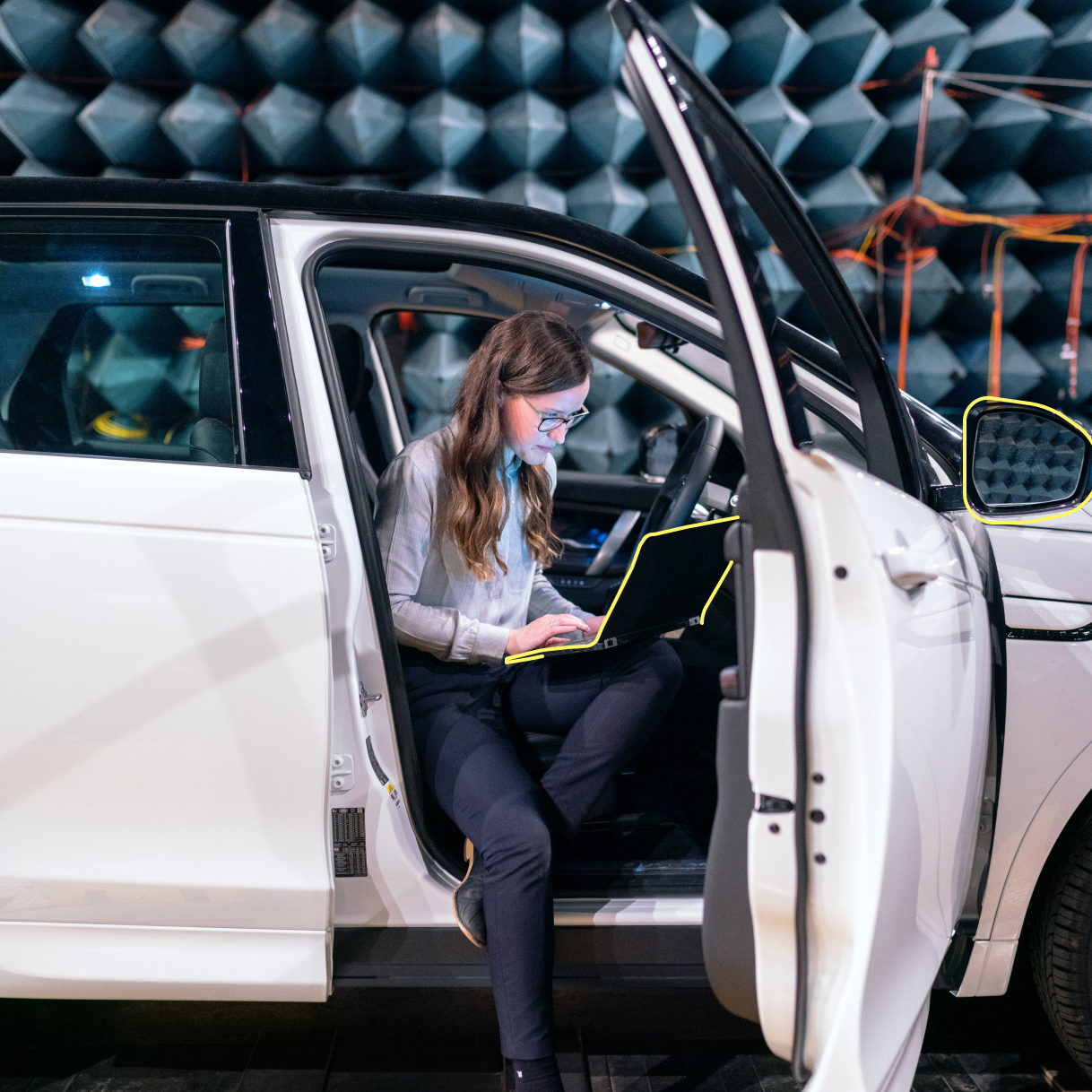 Frau sitzt mit Laptop im Auto